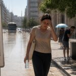 Persona in città sotto il sole intenso con termometro sopra i 40 gradi, immagine sul caldo estremo e i rischi per la salute.