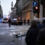 Strada del centro città con mezzi di soccorso e atmosfera di cronaca, in tono sobrio e rispettoso.