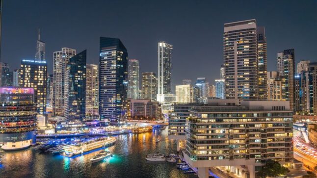 Stunning night view of Dubai Marina with illuminated skyscrapers and reflections on the water.